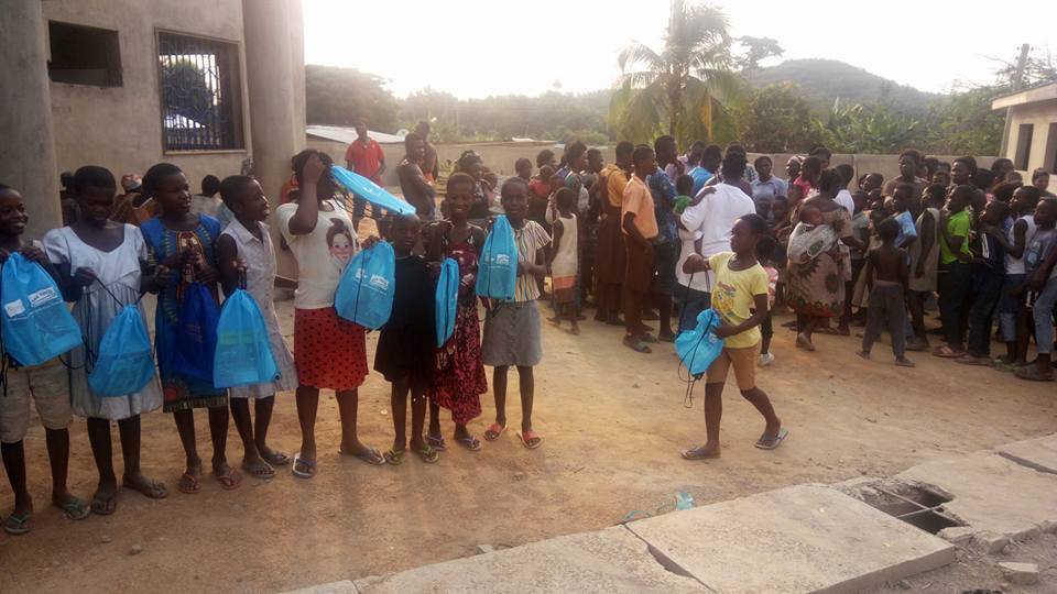 A group of children holding donation bags received at a PROaid Africa community outreach